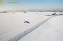 Vue aérienne du paramoteur survolant une route en hiver dans les champs