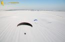 Paramoteur survolant un champ enneigé en hiver vu du ciel