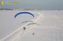 Parapente motorisé suivant une route enneigée avec un panneau d'avertissement