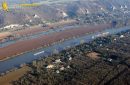 Barges and transport boats on the Seine river seen from the sky at Haute-Isle en Vexin